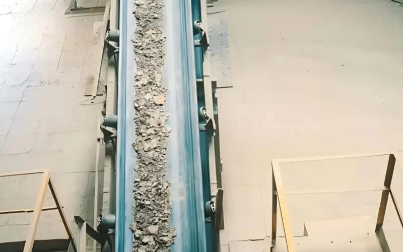 The conveyor belt in the image shows material deviation, with the entire load shifting to the left.