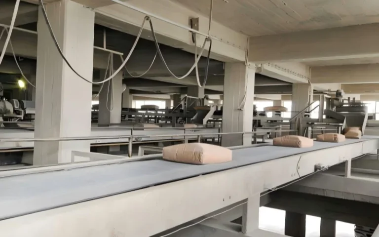 Cinta transportadora de producción de fábrica de cemento con sacos de cemento llenos. Interiores de la fábrica de cemento. Cinta transportadora de cemento.